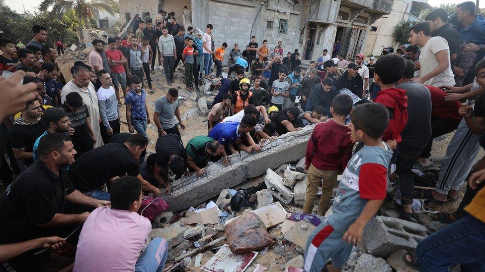 Civil defence teams and Palestinian locals dig the rubble of destroyed house in Khan Yunis