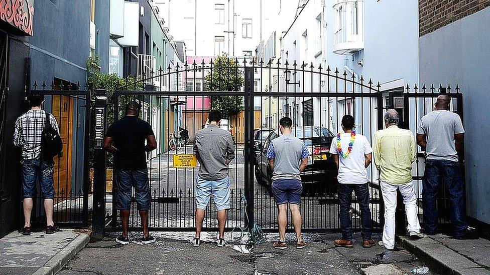 Men urinate on the gates of a mews street during the Notting Hill Carnival 2013