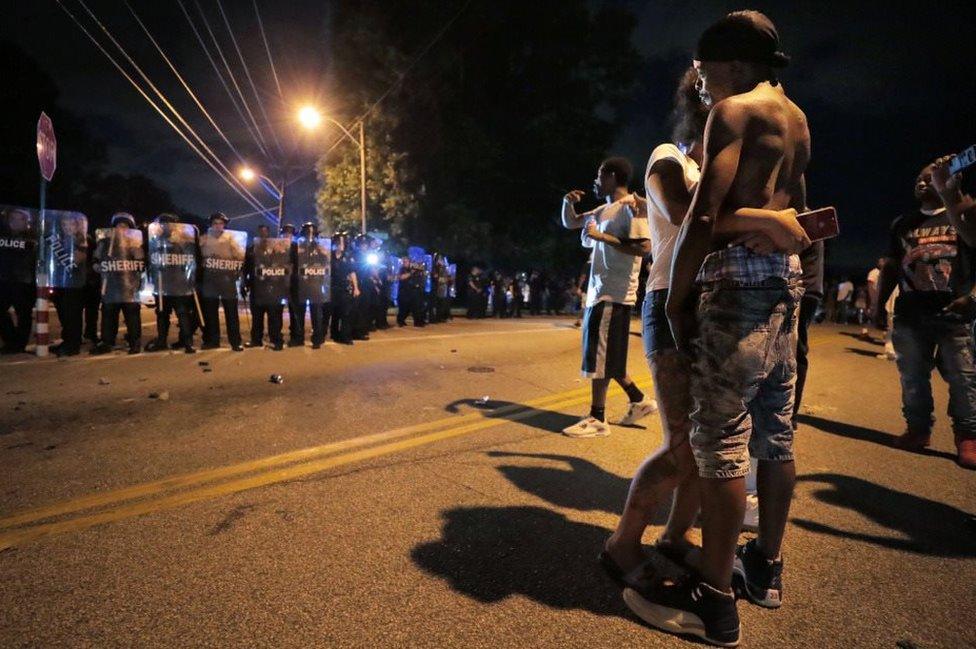 A man identified as the victim's father is consoled at the scene of the standoff