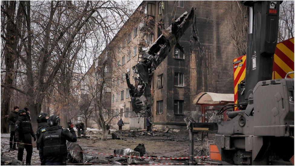 The debris of a shot down Russian missile is removed from opposite a residential building in Kyiv