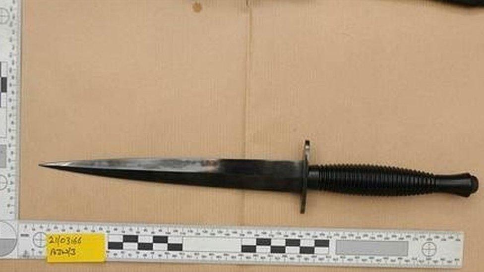 Military of hunting knife seen next to a measuring tape