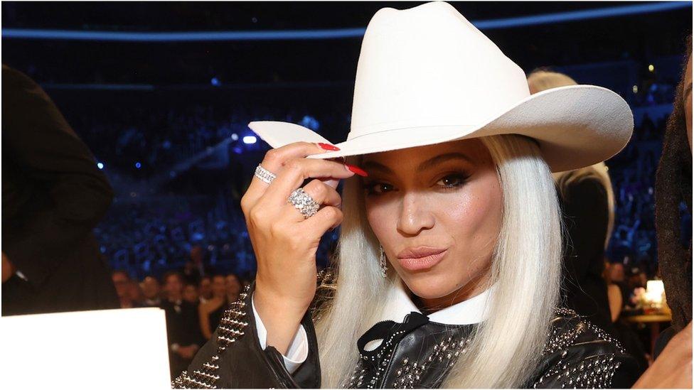 Beyonce, wearing a white cowboy hat, pouts at the camera