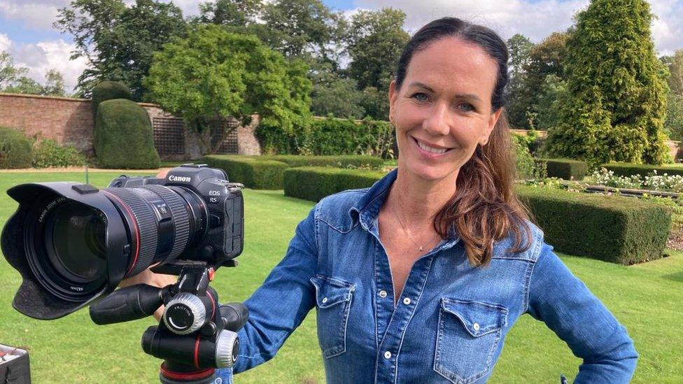 Woman with long dark hair holds DSLR camera on a tripod