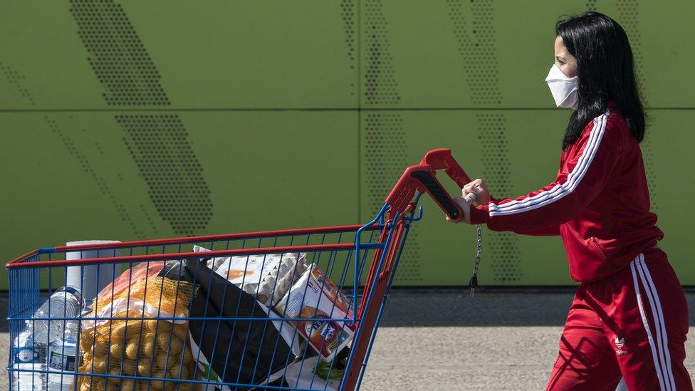 A woman wearing a protective facemask leaves a supermarket in Illzach, eastern France, 16 March 2020