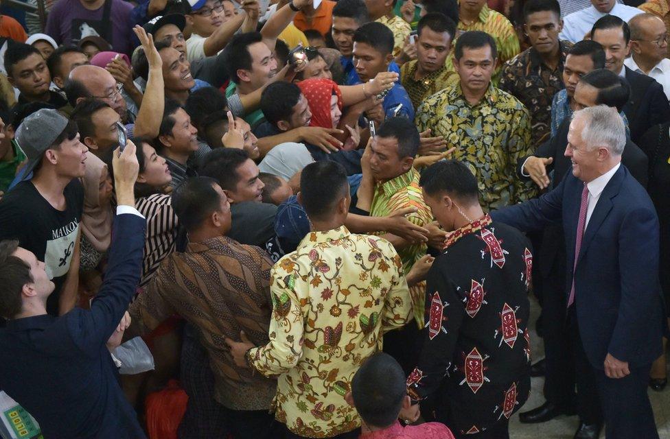 Indonesians rush to shake hands with Australia's Prime Minister Malcolm Turnbull (R) and Indonesian President Joko Widodo (obscured) as they visit the Tanah Abang retail market in Jakarta on November 12, 2015. Turnbull made his first visit to Indonesia since taking power, seeking to repair a key relationship strained by repeated crises under his conservative predecessor. AFP PHOTO / ADEK BERRY / POOL (Photo credit should read ADEK BERRY/AFP/Getty Images)