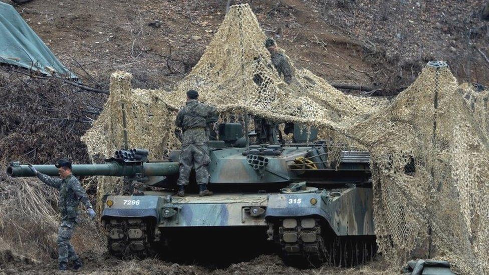 South Korean soldiers set up a camouflage net over their tank during a military exercise near the demilitarised zone separating the two Koreas in Paju, South Korea (07 March 2016)