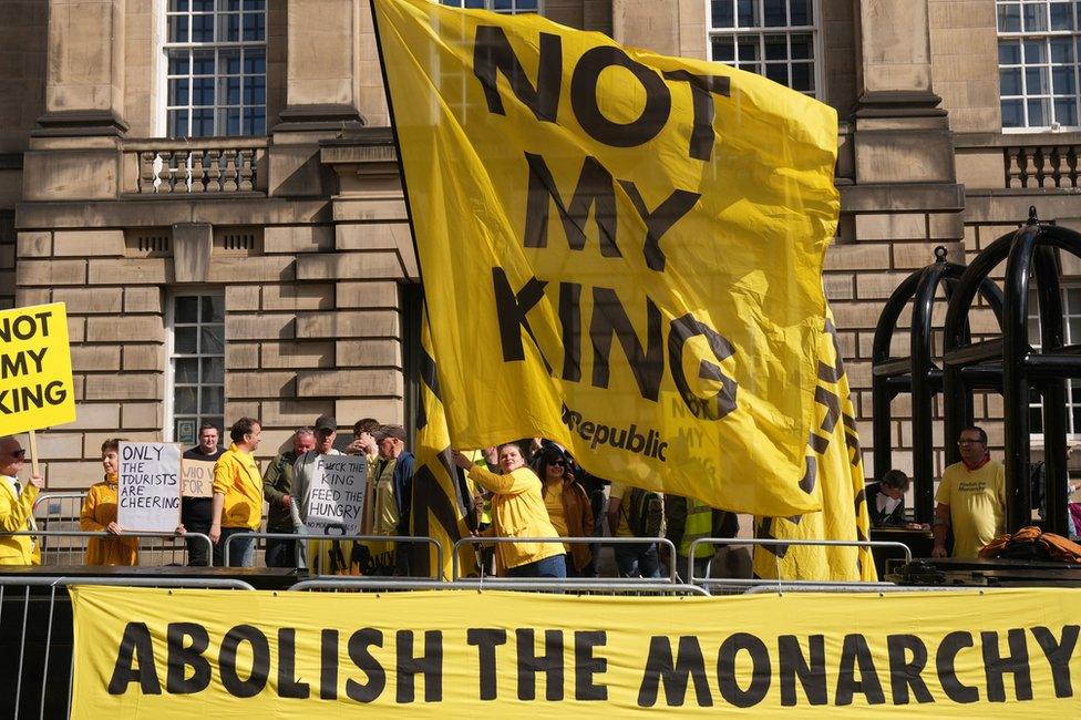 Protesters wave a large yellow flag with the words 'Not my king' and another banner fixed to barriers which reads 'Abolish the monarchy'