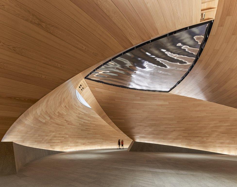 An interior of a building with a sloping wooden ceiling