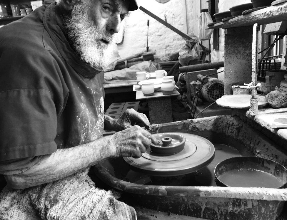 A potter is working with clay on the pottery wheel