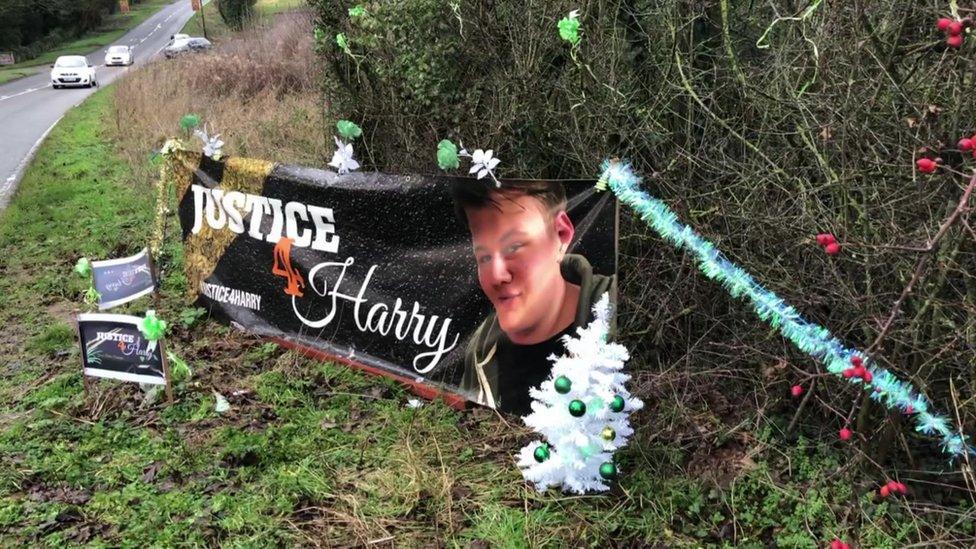 A Christmas tree and decorations surround a banner for Harry Dunn outside RAF Croughton