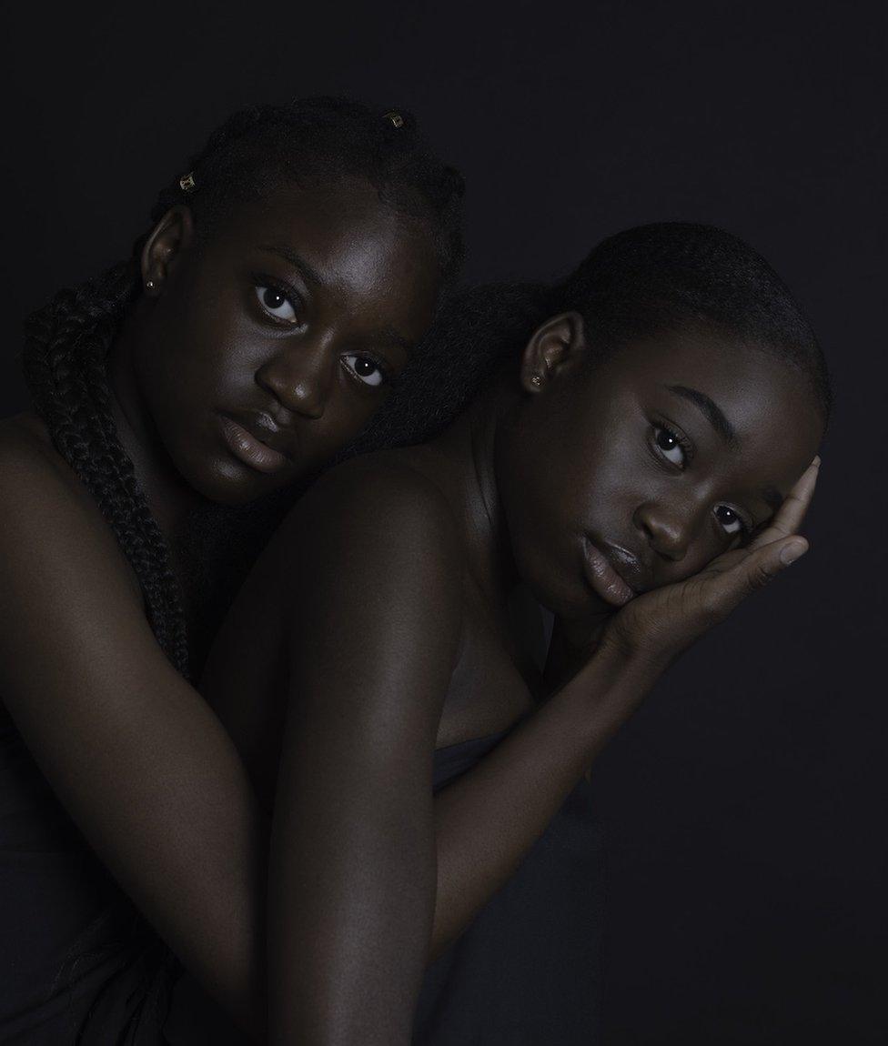 A portrait of two women, one is holding the other's head