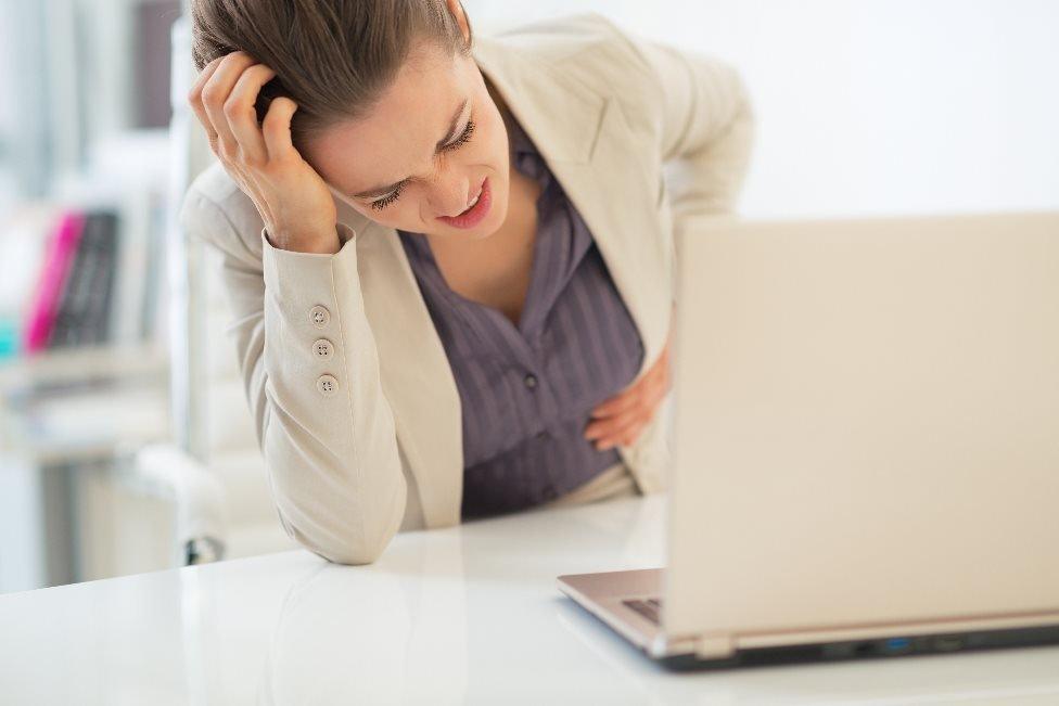 Woman holds her stomach at work