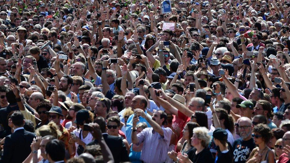 A large crowd take pictures on Las Ramblas.