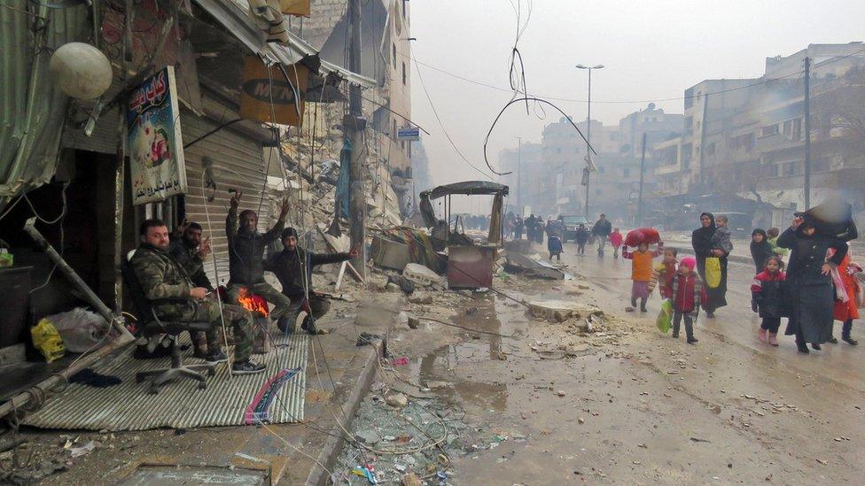 Syrian pro-government troops gesture as residents, fleeing violence in the restive Bustan al-Qasr neighbourhood, arrive in Aleppo's Fardos neighbourhood, 13 December 2016, after regime troops retook the area from rebel fighters. Syrian rebels withdrew from six more neighbourhoods in their one-time bastion of east Aleppo in the face of advancing government troops, the Syrian Observatory for Human Rights said.