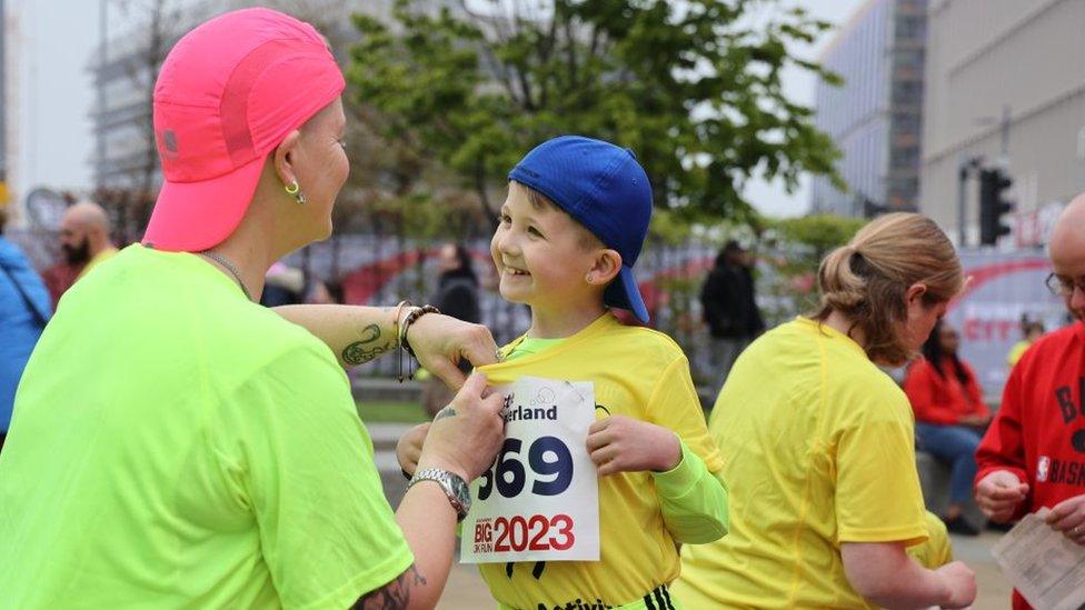 A youngster gets ready for his run with his number being pinned on to his shirt