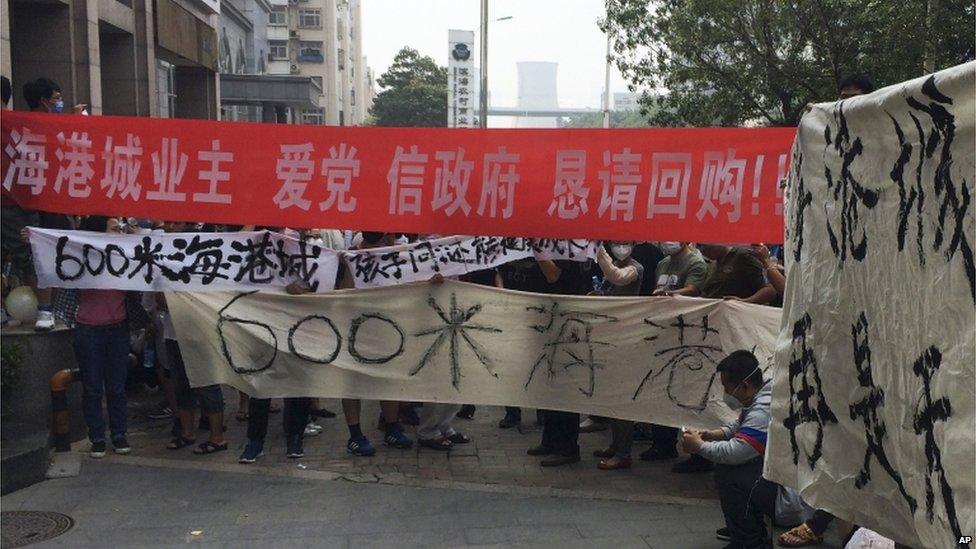 Residents hold banners and placards as they stage protest outside a hotel where officials held daily media conferences in northeastern China's Tianjin municipality Monday, 17 August 2015.