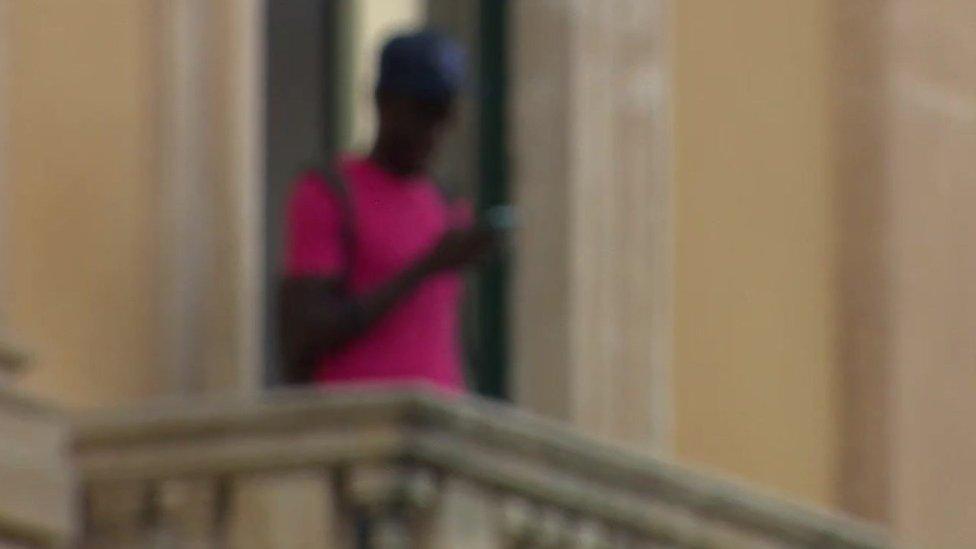 A young migrant stands on a balcony in Rome