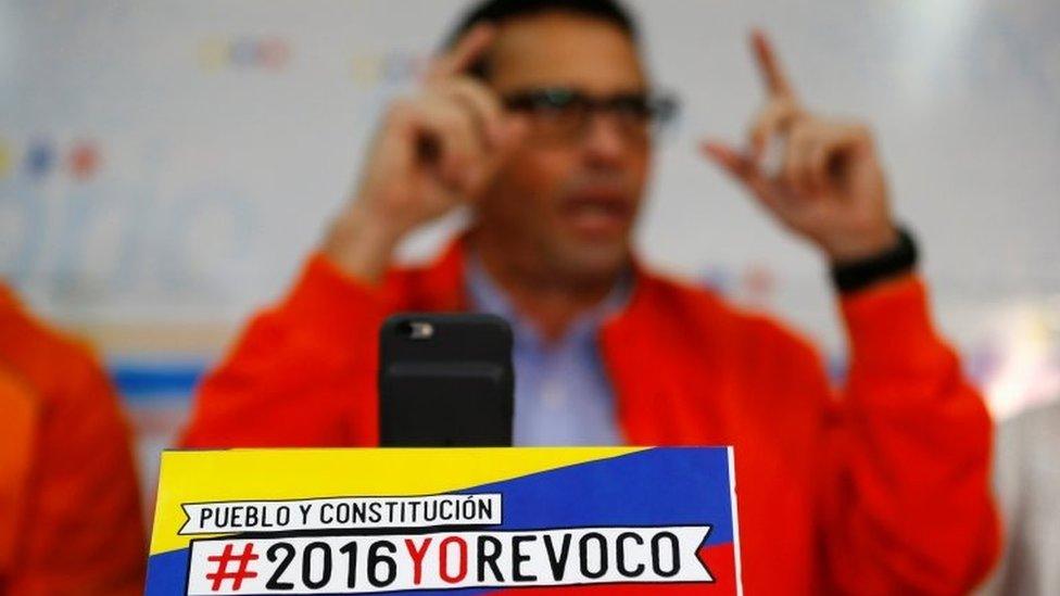 Venezuelan opposition leader and Governor of Miranda state Henrique Capriles gestures while he talks to the media during a news conference in Caracas, Venezuela June 10, 2016. The sign reads: "People and constitution. 2016, I recall".