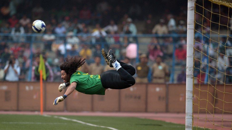 Former Colombian goalkeeper Rene Higuita kicks the ball to save a goal during an exhibition match between the Brazilian Masters and Indian All Stars in Kolkata on December 8, 2012