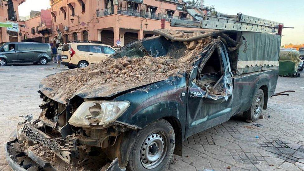 A destroyed truck after bricks and other rubble has fallen on top of it