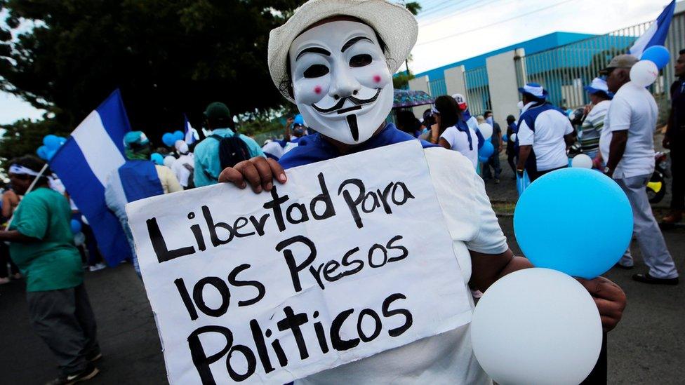 A masked anti-government protester holds a sign reading "Freedom for political prisoners" in Managua, Nicaragua on 9 September 2018.