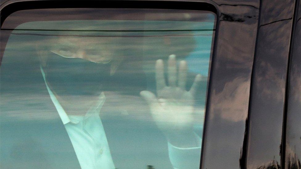 President Donald Trump waves to supporters as he briefly rides by in the presidential motorcade in front of Walter Reed National Military Medical Center