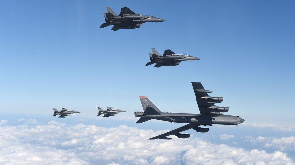 A US B-52 bomber in flight flanked by fighter jets