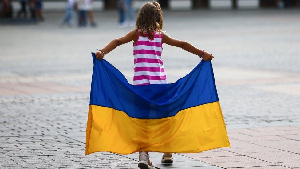 An image of a young girl holding a Ukrainian flag