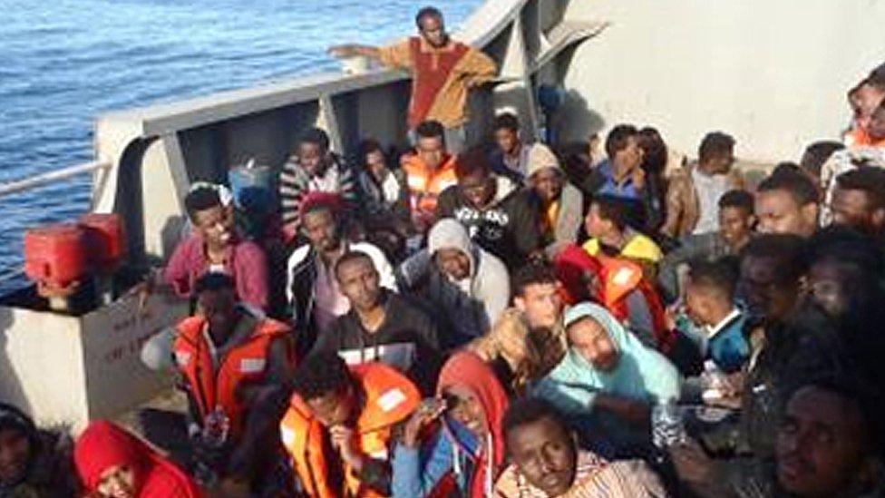 Migrants sit on board a cargo ship in the Mediterranean