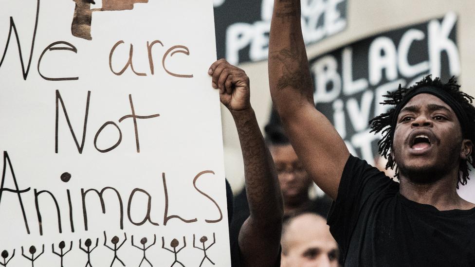 A man next to a sign that reads 'we are not animals'.