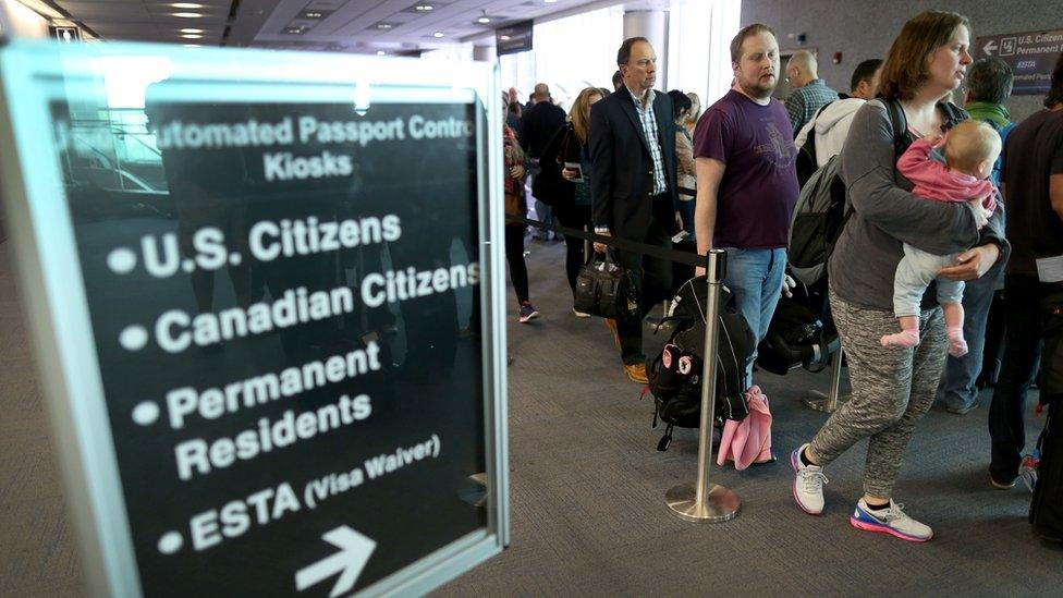 Passengers wait in line to use the Automated Passport Control Kiosks set up for international travelers arriving at Miami International Airport