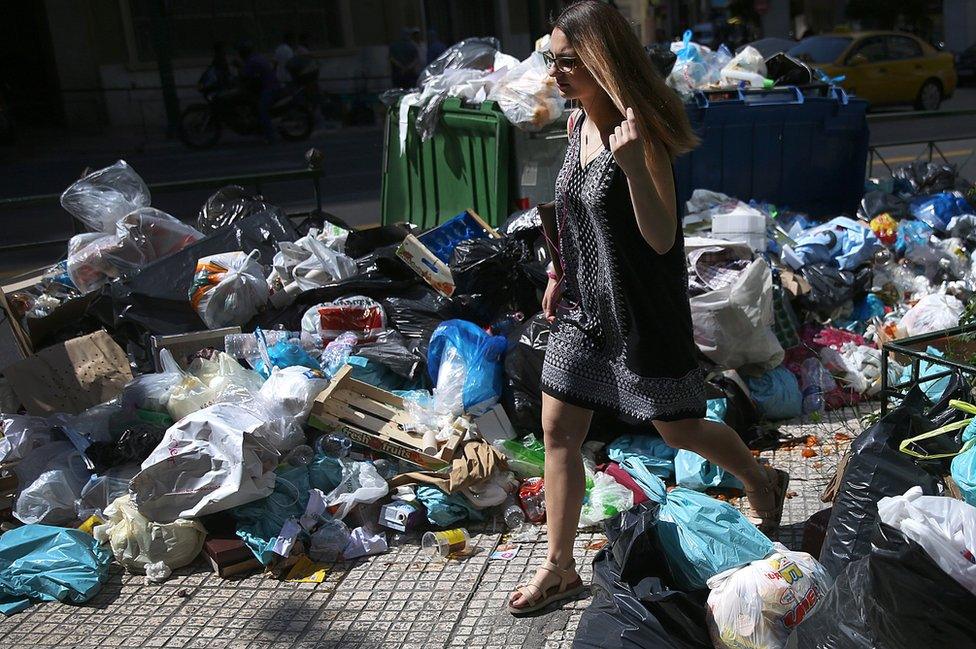 A woman walks through rubbish in Athens