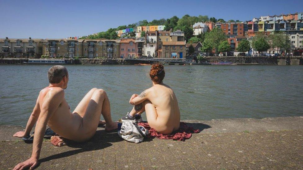 A man and a woman sitting naked by Bristol Harbourside