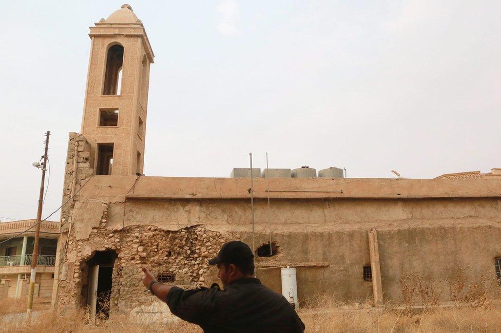 Iraqi Army officer points to the tower of a damaged church in Bartella, east of Mosul, on 24 October 2016