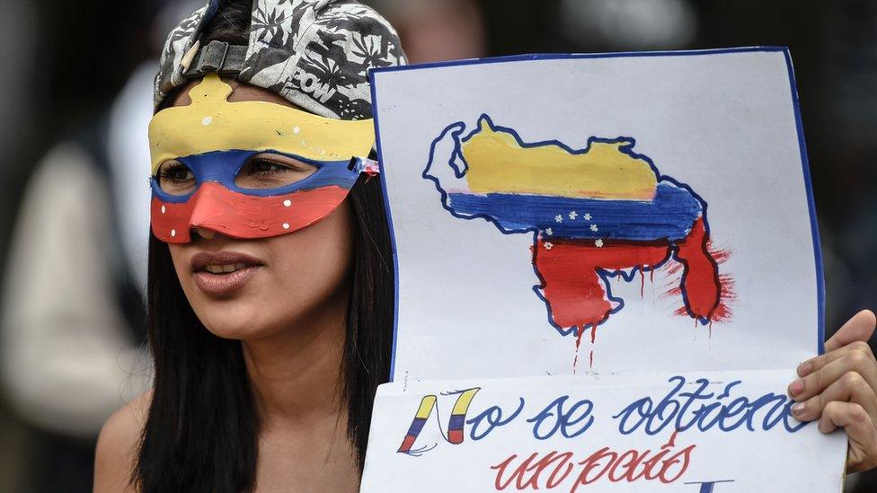 A young opposition activist holds a sign reading "we can't get a different country", during a protest against the government in Caracas, on June 29, 2017