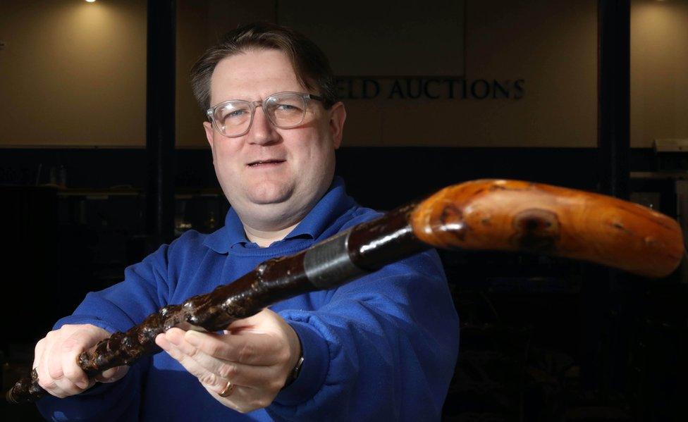 Auctioneer Karl Bennett holds a walking stick formerly belonging to Sir James Craig