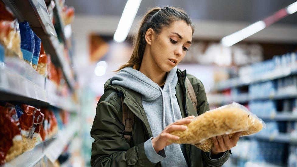 Woman looking at a pack of pasta in a supermarket