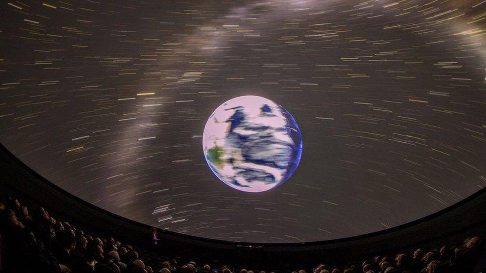 A picture from within a planetarium showing the earth and stars