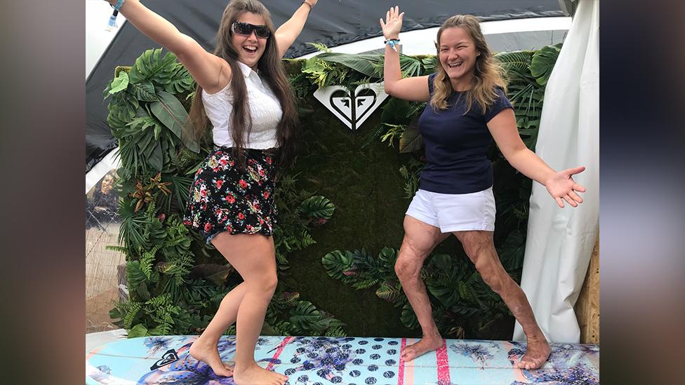 Laura and a friend posing on a surfboard in Bournemouth