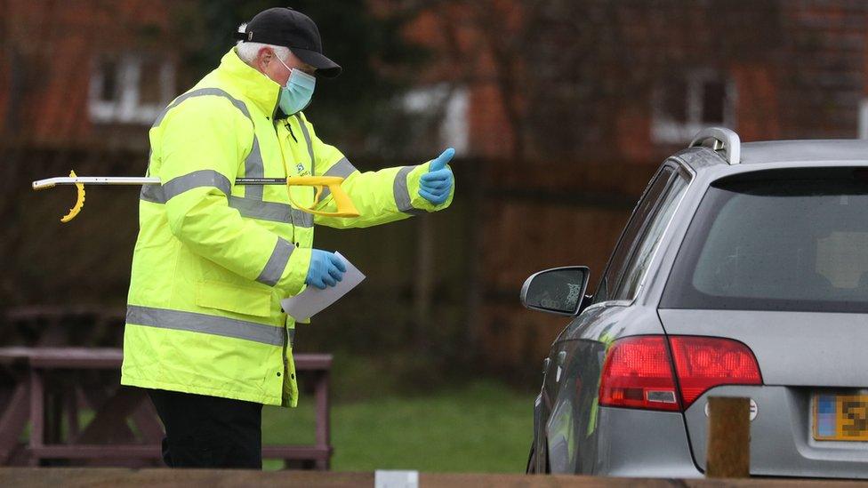 A test and trace worker in the Bramley Inn car park in Bramley, near Basingstoke, Hampshire, speaks to a driver at a surge testing programme with local residents