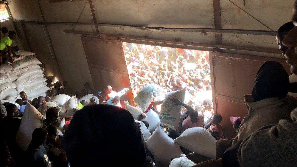 People carry sacks of supplies at a warehouse in Bukuru, Nigeria, 24 October 2020