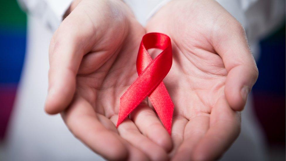 Man holding red aids ribbon