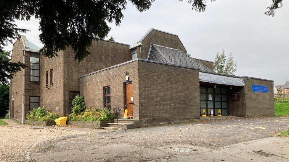 Brick-built 1970s church with glass entrance doors.