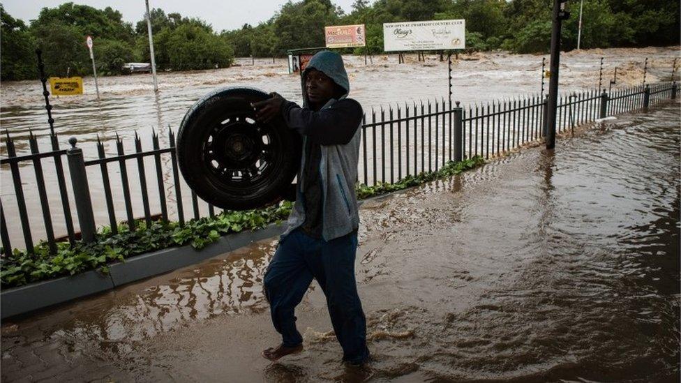 A man working at a car dealership in Centurion retrieves tires floating down river in a flooded area in Centurion, Pretoria, South Africa, 09 December 2011