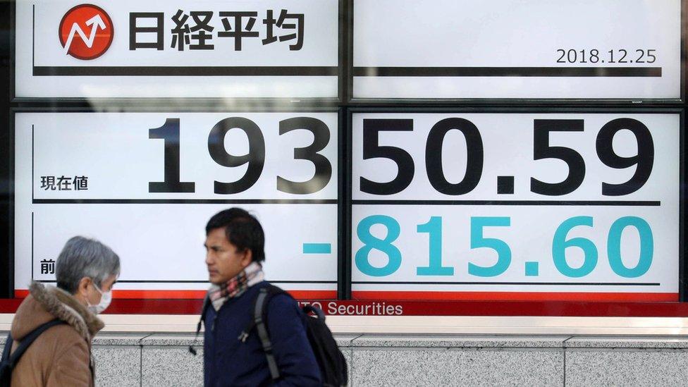 Pedestrians walk past a stock market indicator board in Tokyo, Japan, 25 December 2018