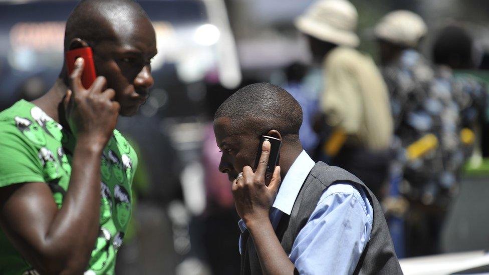 People walk while speaking on the phone on 1 October 2012 in Nairobi, Kenya.