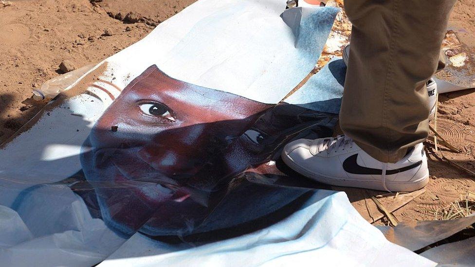 Someone standing on a torn poster of Yahya Jammeh after he lost elections in December 2016