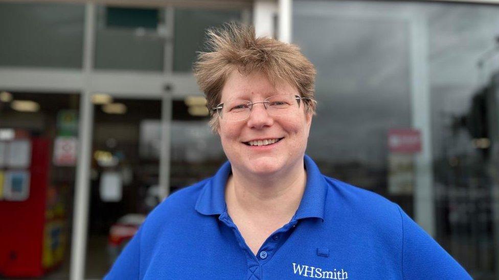 Jen Roberts with short fair hair and glasses wearing a WH Smith t-shirt