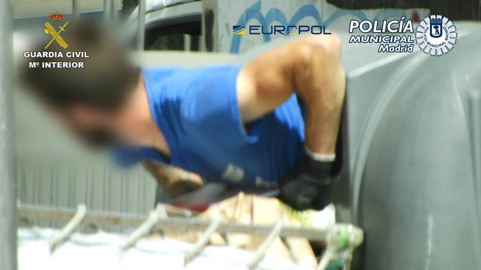 A man crawling out of a recycling bin in Madrid