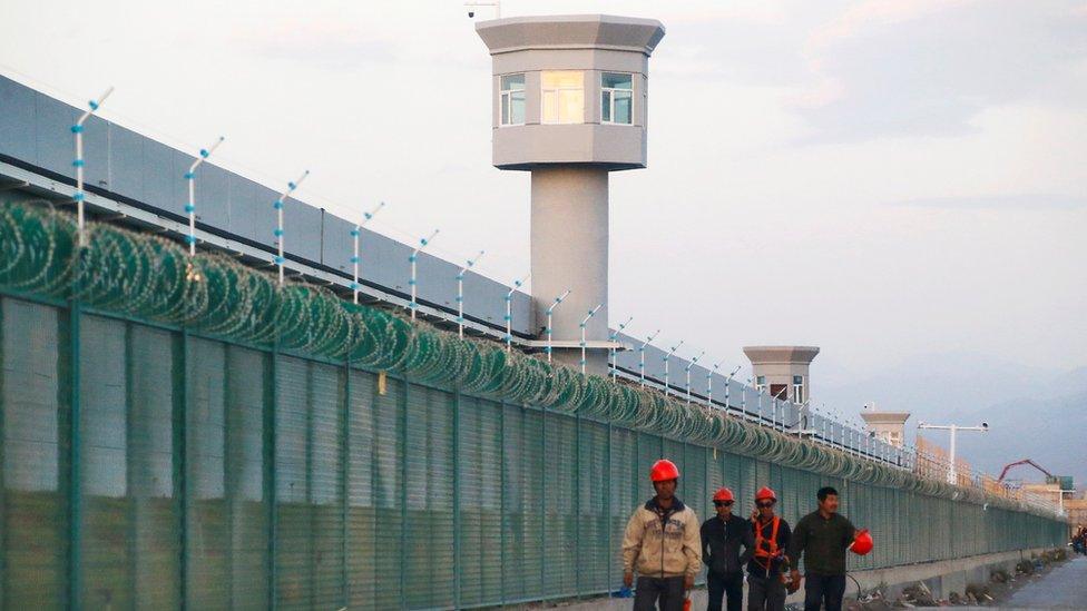 Workers walk by the perimeter fence of what is officially known as a vocational skills education centre in Dabancheng in Xinjiang Uighur Autonomous Region, China September 4, 2018.